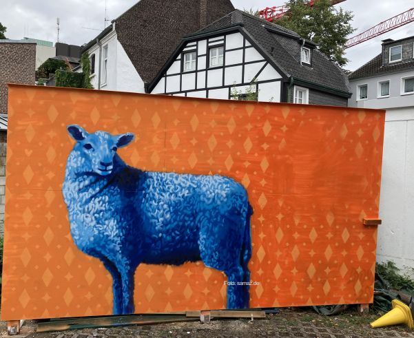 Foto - ein auf eine orange Wand gesprühtes Bild eines blauen Schafs.